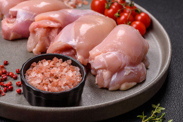 Fresh chicken fillet on a dark concrete table with spices and herbs