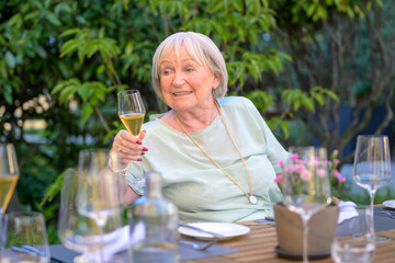 Elderly Woman Toasting with Champagne at an Outdoor Dinner