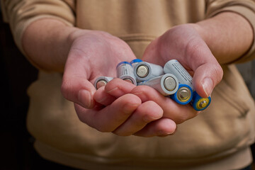 Close-Up of Hands Holding AA Batteries, Highlighting Power, Energy, and Sustainable Practices for...