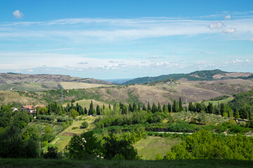 idllic italian mountain house with cypress tress road, landscape with hills and blue sky