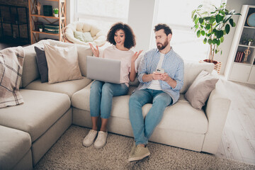 Obraz premium Photo of two people girl amazed look netbook ads guy sit couch feel unhappy in room apartment