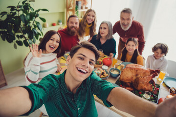Photo of cheerful happy big family celebrating thanksgiving day enjoying time together taking selfie indoors room home