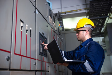 Electrical engineer check the operation of the main electrical control panels and switches, record values ​​on tablets, electrician inspect the electrical systems in the factory.
