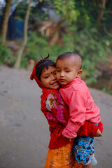 South asian young siblings are together in red dress 