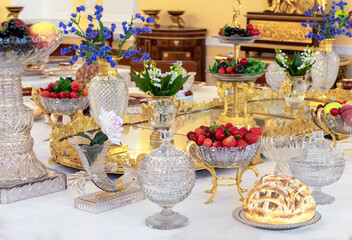 Strawberries in a crystal vase on a richly decorated table. Table setting option.