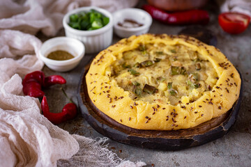 Pie with potatoes and onions for lunch. Tart with potatoes and onions on a gray background. Close-up