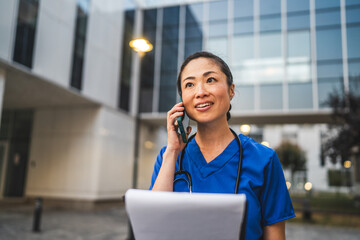 happy japanese woman doctor talk on cellphone and hold clipboard