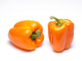 Two wet orange bell peppers on white.