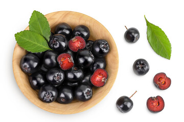 Chokeberry with leaf in a wooden bowl isolated on white background. Black aronia. Top view. Flat lay