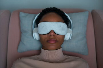Ketamine therapy session for mental health, patient with eye mask and headphones resting on gray pillow