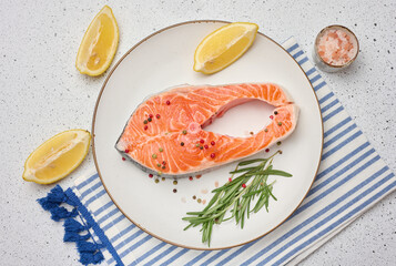 Raw piece of salmon fish steak in round white plate on a white background