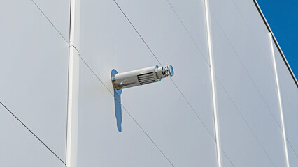 Stainless steel ventilation chimney on the wall of a new warehouse or factory. 