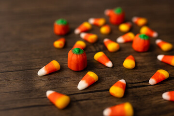 close-up of scattered candy corns and pumpkin candies against a wooden background
