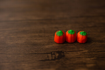 close-up of mini candy pumpkins against a wooden background, seasonal 