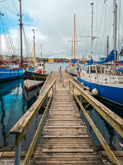 Fototapeta premium Nautical Scene with Dock and Boats Looks Through to Beautiful Views of the Harbor in Tórshavn, the Capital of the Faroe Islands. Streymoy, Faeroe Islands.