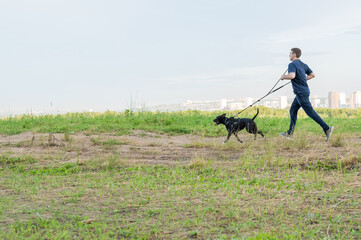 Man running with pit bull terrier outdoors. 