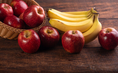 Bananas and apples on rustic wooden table, selective focus.