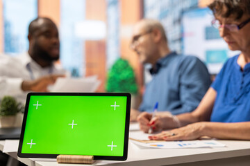 Financial counseling discussion with a tablet showing green screen on display, old people discussing with a banker to find a pension plan option for retirement stability. Close up.