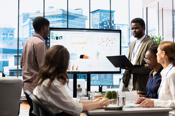 Business associates collaborating at the conference table in boardroom, utilizing smart technology...