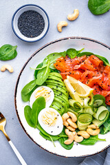 Keto diet salad with salmon, avocado, spinach, eggs and cashew. Gray table background, top view