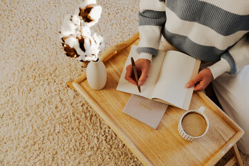 Cozy journaling setup with coffee and cotton branches on a wooden tray. Peaceful writing moments,...