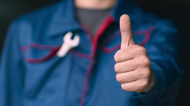 Great auto repair service. Close up of professional mechanic in uniform gesturing thumb up to camera, approval concept