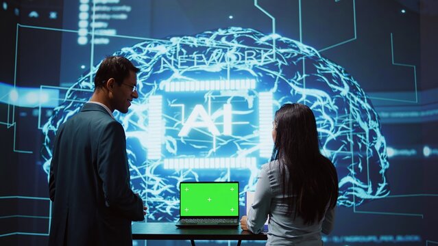 Startup coworkers brainstorming ways to use AI on chroma key notebook to improve data driven decisions. Technicians using mockup laptop to improve artificial intelligence tech, camera B