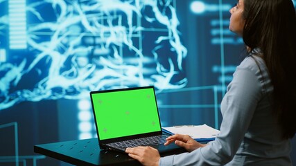 Startup employee looking over charts, using AI software on green screen laptop to take data driven decisions. Indian woman developing innovative artificial intelligence solutions for company, camera A