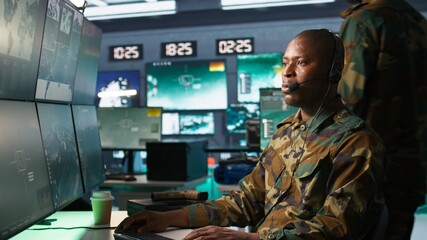Army specialist working in war room operating surveillance tech, evaluating target data, talking in voice call. Dispatcher keeping in touch with allied troops engaging enemy forces, camera B