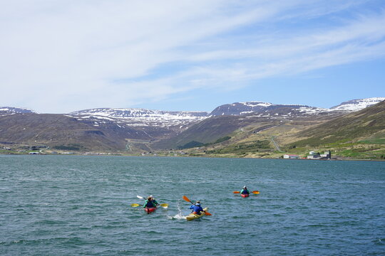 Isafjordur, Iceland - scenic family boat kayak excursion on Pollut during sunny day with snow covered mountains of Ísafjarðarbær in the background