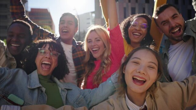 Group multiracial joyful young friends posing having fun looking excited at camera together in city street. Generation z community cheerful people waving happily and celebrating raising arms outdoor