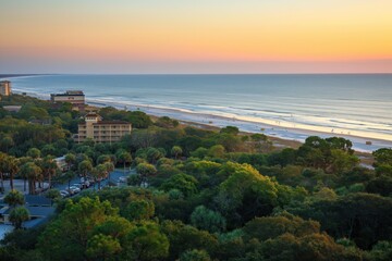 Obraz premium Beach scene at Coligny on Head Island. Ocean view at sunset with palm trees and hotels in foreground. Soft focus on blue waters and sandy shore. People relax under umbrella.