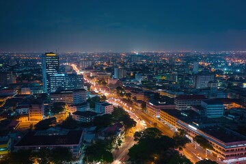 Nighttime aerial view of Accra city, Ghana. Cityscape with modern architecture, old buildings, and infrastructure like roads, bridges, and railways. People are visible on streets, moving through city.