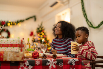 Fototapeta premium family moment during Christmas as they exchange gifts around festive dinner table. The table with Christmas-themed tableware, candles and delicious food. The room is adorned with holiday decorations.