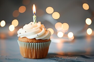 Birthday cupcake with burning candle on blurred lights background. Delicious dessert with cream frosting and colorful sprinkles. Perfect for celebrating first year, happy holiday, or festive party.