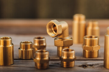 Brass plumbing fittings lying on a rustic wooden table on a sunny day (selective focus)