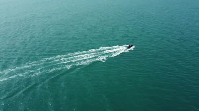 Jetsky aerial drone tracking video sailing on Anyer beach at high speed. High speed speedboat in blue sea.