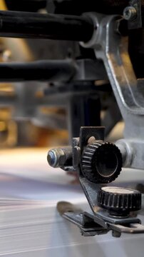 Printing machine prints paper in typography. Newspaper or tabloid processed on conveyor belt line. Freshly printed pages move through plant factory, ready for distribution. Production in action