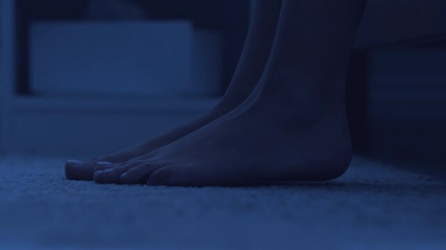 Feet of woman stepping out from bed and walking aside, close up