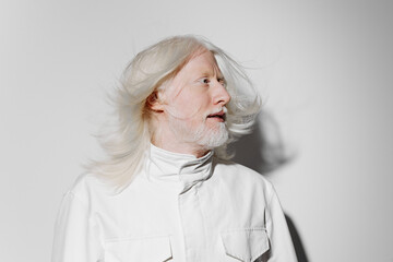 Portrait of an elderly man with long white hair against a plain white background, showcasing...