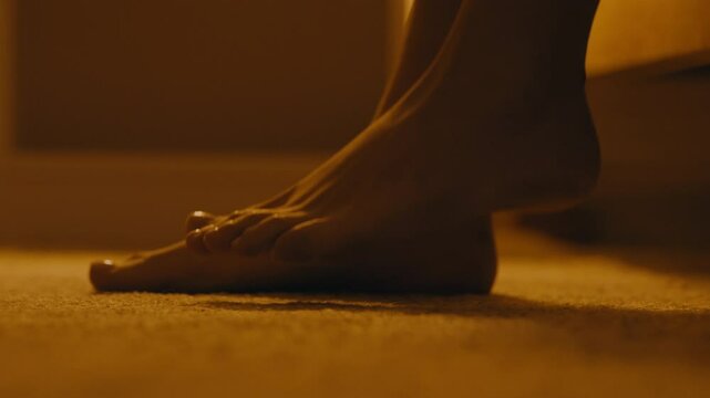 Night awakening. Female feet getting out of bed and going away, close up
