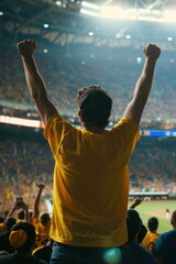 Vibrant yellow shirted man celebrates winning baseball game in large stadium filled with cheering fans. Arms raised as stands triumphantly, lit up with joy reflecting excitement of crowd around.