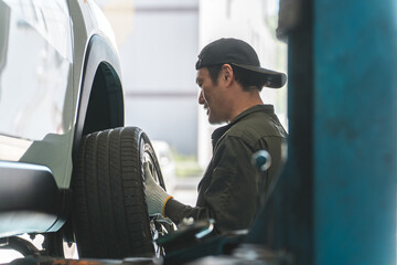 リフトアップした車のタイヤを脱着する整備士の男性  © buritora