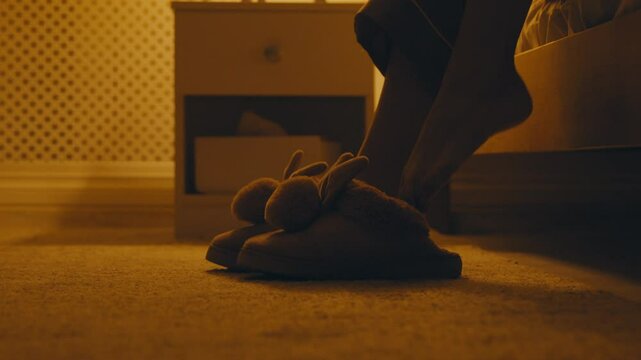 Close up of woman getting out of bed, wearing cozy fluffy slippers and going away