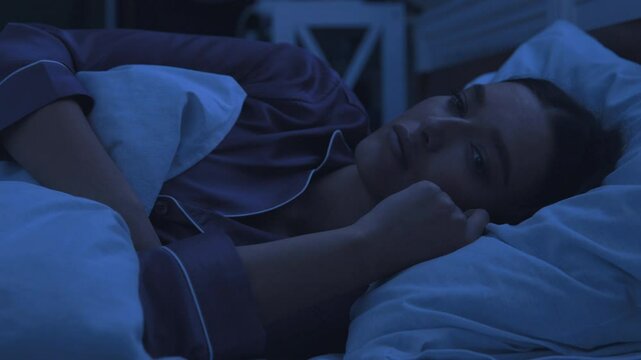 Woman at night suffering of insomnia, not able to sleep in bed
