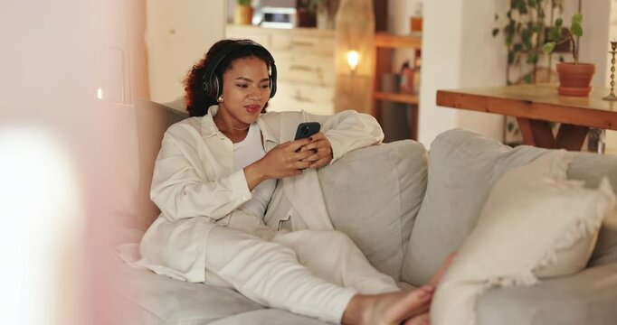 Headphones, phone and woman on sofa in home listening to music, podcast or playlist for blog review. Relax, cellphone and female freelance critic with audio tech for streaming new album at house.
