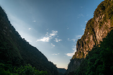 Silhouettes of mountain and vegetation on blue sky with beautiful clouds as space for writing that...