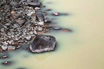 textures and patterns in a river with colors in the water and space to write works as wallpaper and desktop blue brown tones and lines of currents and streams volcanic rocks with reflection in ponds