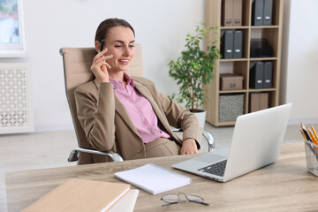 Fototapeta premium Smiling businesswoman working at table in office