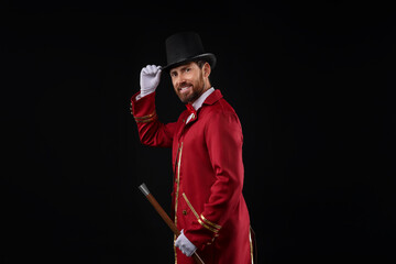 Portrait of showman in red costume and hat on black background